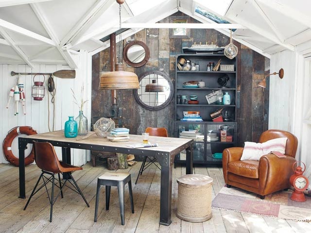 Décoration bord de mer : cabane en bois blanchi, miroirs ronds, bouée et fauteuil en cuir