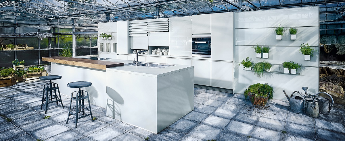 Cuisine blanche avec îlot et comptoir en bois, installée sous une verrière