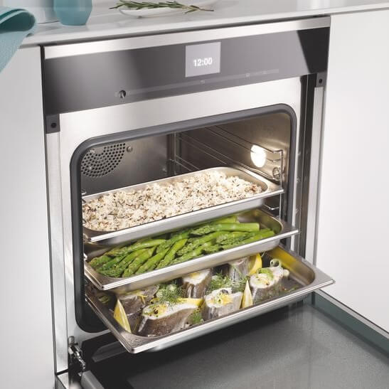 Four vapeur combiné ouvert, trois plats en cuisson : riz, asperges et poisson